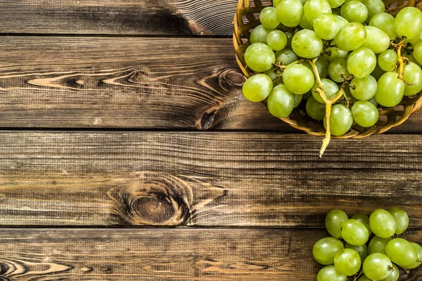 Cambada de uvas verdes na cesta, frutos do outono em fundo de madeira — Fotografia de Stock