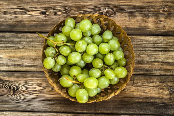 Cambada de uvas verdes na cesta, frutos do outono em fundo de madeira — Fotografia de Stock