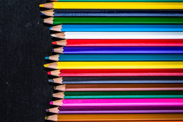 Fondo colorido de los útiles escolares, lápices de colores en negro, concepto de vuelta a la escuela —  Fotos de Stock