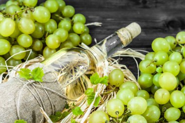 Yeşil üzüm gelen beyaz şarap şişesi. Yaşlı ahşap kiler içinde ev yapımı şarap.