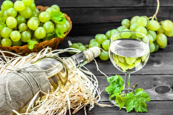 Garrafa de vinho branco e copo de vinho de uva verde. Vinho caseiro sazonal em despensa de madeira . — Fotografia de Stock