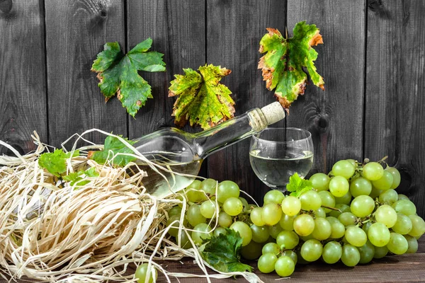 Garrafa de vinho branco e copo de vinho de uva verde. Vinho caseiro sazonal em despensa de madeira . — Fotografia de Stock