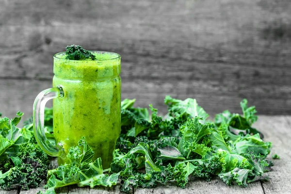 Vegetable smoothie with green kale leaves on wooden table