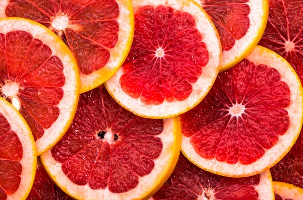 Texture of grapefruit slices, close view, overhead, red citrus backgrounds — Stock Photo, Image