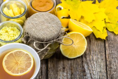 Rustik ahşap zemin üzerine limon çayı. Malzemeler bir cam kavanoz, zencefil ve bal. Sonbahar yaprakları ile kavramı.