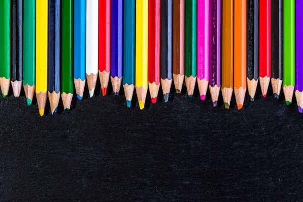 Matériel scolaire coloré fond, crayons de couleur sur noir, concept de retour à l'école — Photo