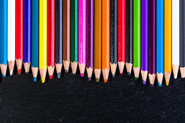 Matériel scolaire coloré fond, crayons de couleur sur noir, concept de retour à l'école — Photo