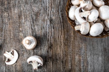Ahşap masa, ek yükü bir sepet içinde taze champignon mantar