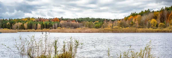 Bosque de otoño sobre el lago, vista panorámica de otoño con árboles coloridos y cielo nublado — Foto de Stock