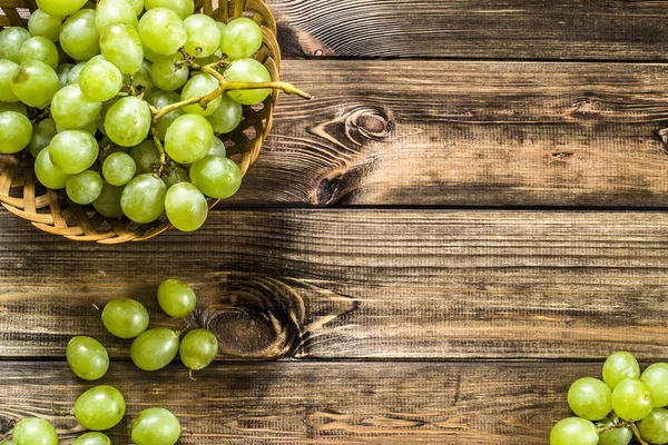 Cambada de uvas verdes na cesta, frutos do outono em fundo de madeira — Fotografia de Stock