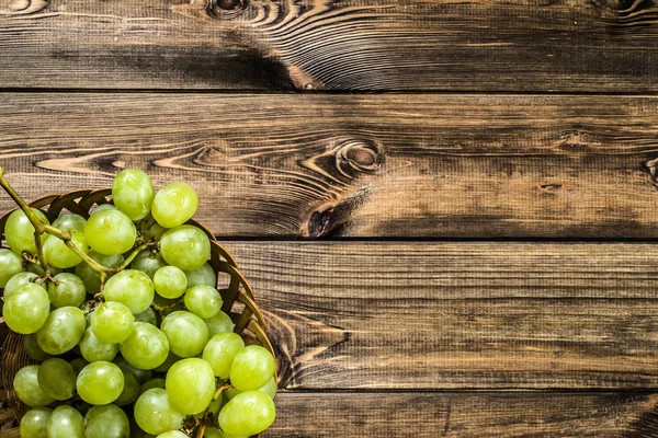 Demet-in Yeşil üzüm sepetindeki, ahşap arka plan üzerinde sonbahar meyve