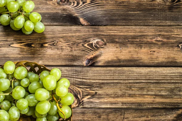 Demet-in Yeşil üzüm sepetindeki, ahşap arka plan üzerinde sonbahar meyve