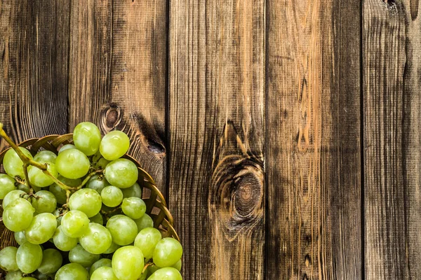 Demet-in Yeşil üzüm sepetindeki, ahşap arka plan üzerinde sonbahar meyve