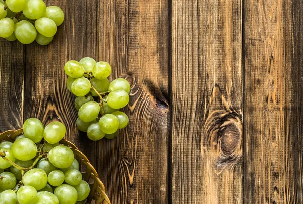 Cambada de uvas verdes na cesta, frutos do outono em fundo de madeira — Fotografia de Stock