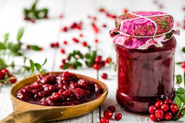 Kaşık ve kavanoz reçel ile kızılcık Beyaz ahşap zemin üzerinde 