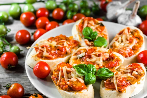Tradiční italský předkrm nebo bruschetta zapečená s rajčaty, bazalkou a sýrem — Stock fotografie