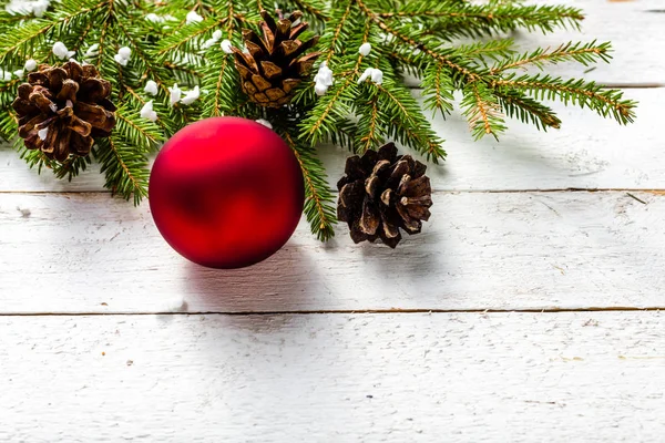 Fondo natalizio con ornamenti su ramo di abete - bagattella rossa su tavole bianche — Foto Stock