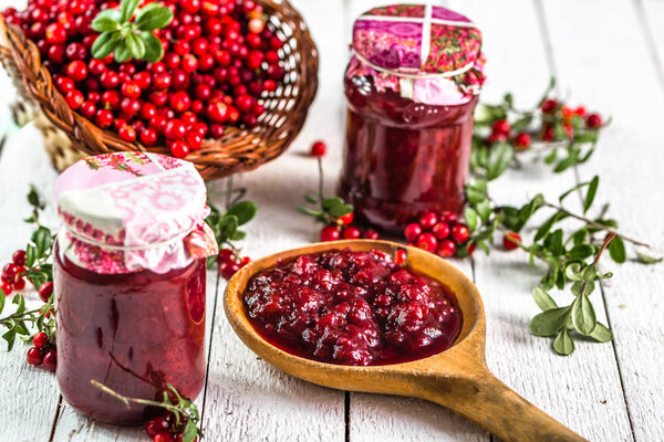 Клюквенное варенье в банке на белом деревянном столе
