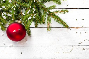 Ahşap arka plan üzerinde süslemeleri ile Noel köknar ağacı. Kar taneleri Beyaz ahşap kurullarında dallarında asılı kırmızı süsler