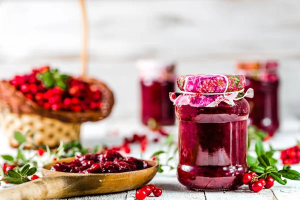 Kaşık ve kavanoz reçel ile kızılcık Beyaz ahşap zemin üzerinde 