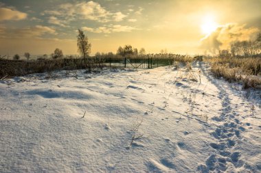 Gün batımından önce karda ayak izleri ile kış manzarası