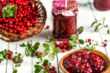 Kaşık ve kavanoz reçel ile kızılcık Beyaz ahşap zemin üzerinde 