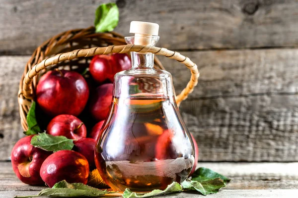 Şarap şişe ya da elma sirkesi, sağlıklı Detoks içecek ahşap arka plan üzerinde organik Kırmızı elma ile