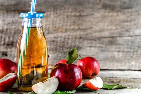 Свіжий яблучний сік на столі, пляшка напою та свіжі яблука на дереві, органічна їжа та концепція здорового способу життя — стокове фото