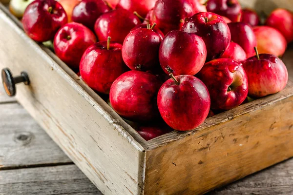 Ahşap kutusunda, rustik arka plan üzerinde taze elma yığını masada kırmızı elmalar