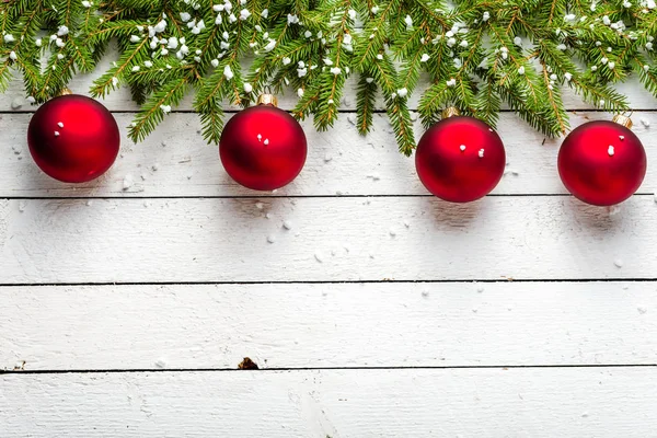 Borde navideño festivo con bolas rojas en ramas de abeto y copos de nieve sobre fondo de madera blanca — Foto de Stock