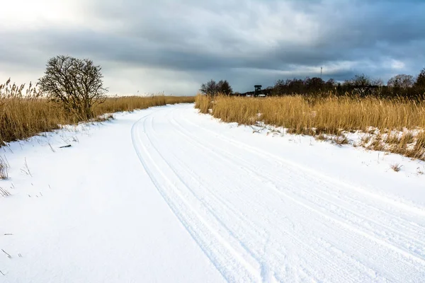 Yolda kar, kış manzarası ile moody gökyüzü göl üzerinde gün batımına