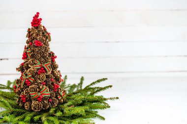 Arka plan beyaz ahşap, çam kozalakları ağaç ve Ladin dalları, kartı boş alanı olan Noel dekorasyonu ile