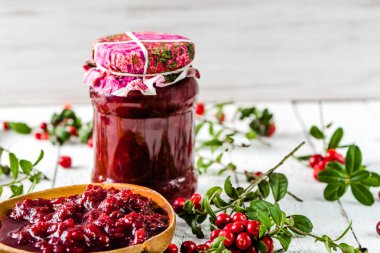 Kaşık ve kavanoz reçel ile kızılcık Beyaz ahşap zemin üzerinde 