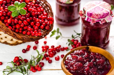 Kaşık ve kavanoz reçel ile kızılcık Beyaz ahşap zemin üzerinde 