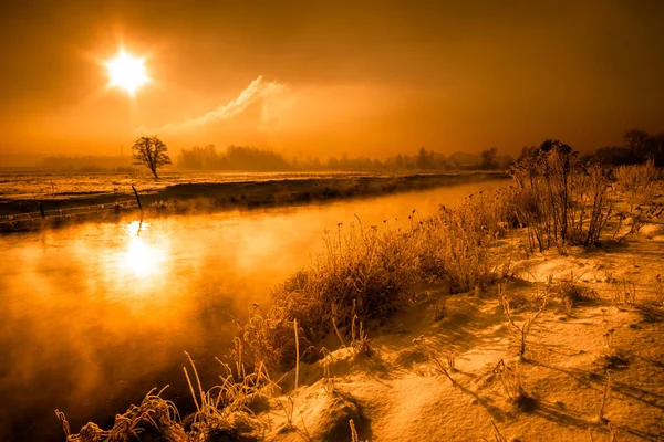 Природный пейзаж зимой над рекой, пейзаж с утренним солнцем на оранжевом небе — стоковое фото