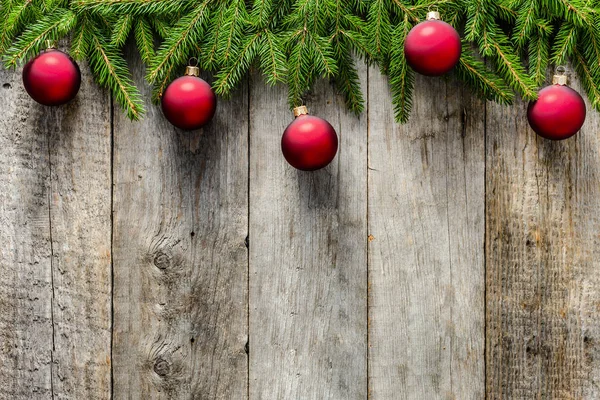 Abete di Natale con decorazioni su sfondo ligneo. Ornamenti rossi appesi a rami su vecchie tavole di legno — Foto Stock