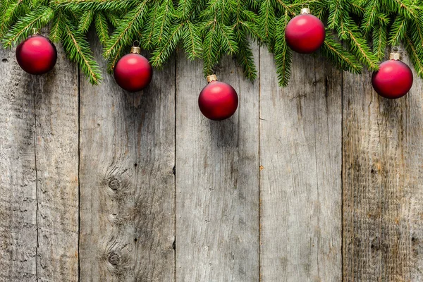 Ahşap arka plan üzerinde süslemeleri ile Noel köknar ağacı. Eski ahşap kurullarında dalları üzerinde asılı kırmızı süsler
