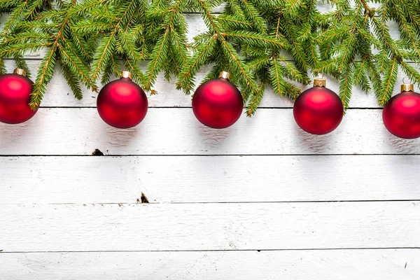Sfondo natalizio con ornamenti su rami di abete su tavole bianche di legno — Foto Stock