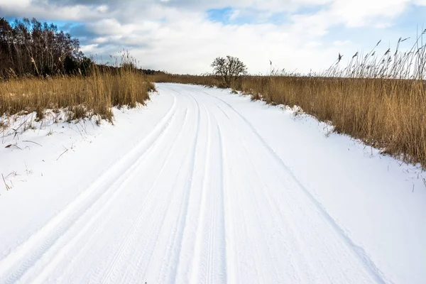Yolda kar, kış manzarası ile moody gökyüzü göl üzerinde gün batımına
