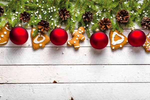 Ozdoby świąteczne z czerwone bombki i pierniki na jodły na białym tle drewnianych — Zdjęcie stockowe