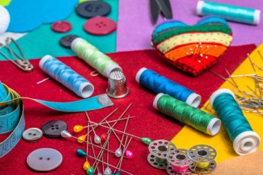 Renkli keçe üzerinde çeşitli dikiş aksesuarları.