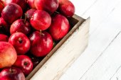 Červená jablka na stole v dřevěné bedně, hromada čerstvé jablko na bílém pozadí