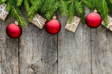 Ahşap zemin, kopya alanı üzerine dekorasyonu ile Noel hediye kutuları ve kırmızı süsleri çam dalları, kart veya Noel üzerinde asılı çerçeve