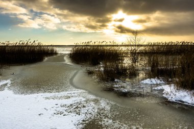 Kış manzarası ile moody günbatımı gökyüzü toplayan buz donmuş gölün