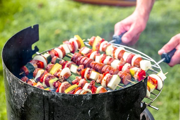 Skewers on barbecue grill in the garden, man preparing shashlik with vegetables and meat, grilling food, outdoor party in the summer garden — Stock Photo, Image