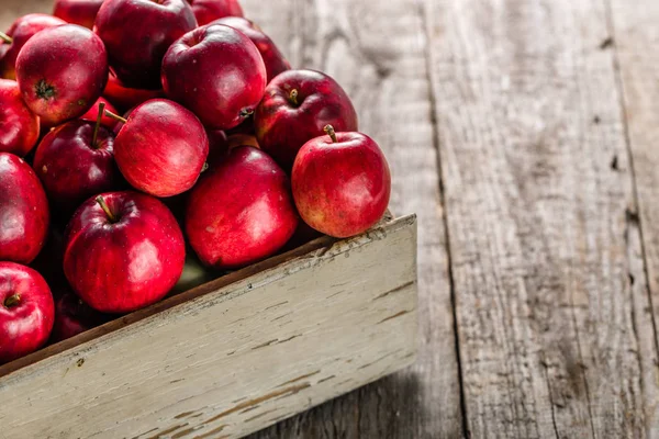 Червоні яблука на столі в дерев'яній коробці, купа свіжого яблука на сільському фоні — стокове фото
