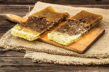 Jüt tutuyordu, seçici odak ile peteğin rustik ahşap zemin üzerine bal ile kaplı.