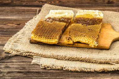 Jüt tutuyordu, seçici odak ile peteğin rustik ahşap zemin üzerine bal ile kaplı.