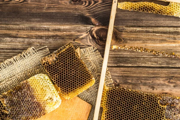 Honeycombs with honey on rustic wood background covered with jute sackcloth, top view. — Stock Photo, Image