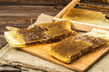 Jüt tutuyordu, seçici odak ile peteğin rustik ahşap zemin üzerine bal ile kaplı.